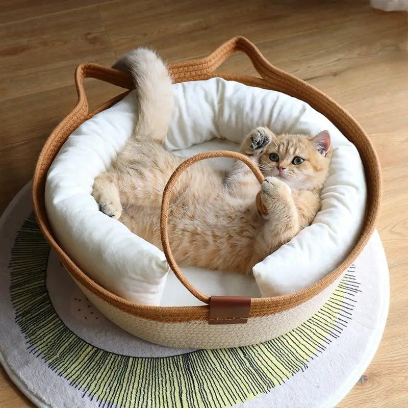 Katze liegt auf dem Rücken im khaki-weissen Katzenbett mit Katzenohren und weissem Polsterrand.