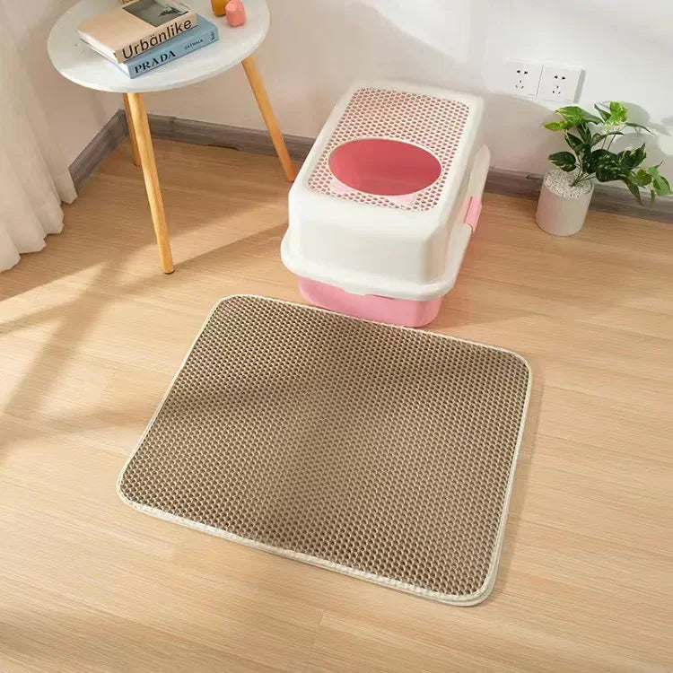 Beige Katzenstreu-Matte mit Wabenstruktur vor einer weiss-rosa Katzentoilette auf Holzboden