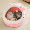 Getigerte Katze liegt in einer rosa Katzenhöhle mit weissem Plüschrand, rosa Schleife und hängendem Spielball