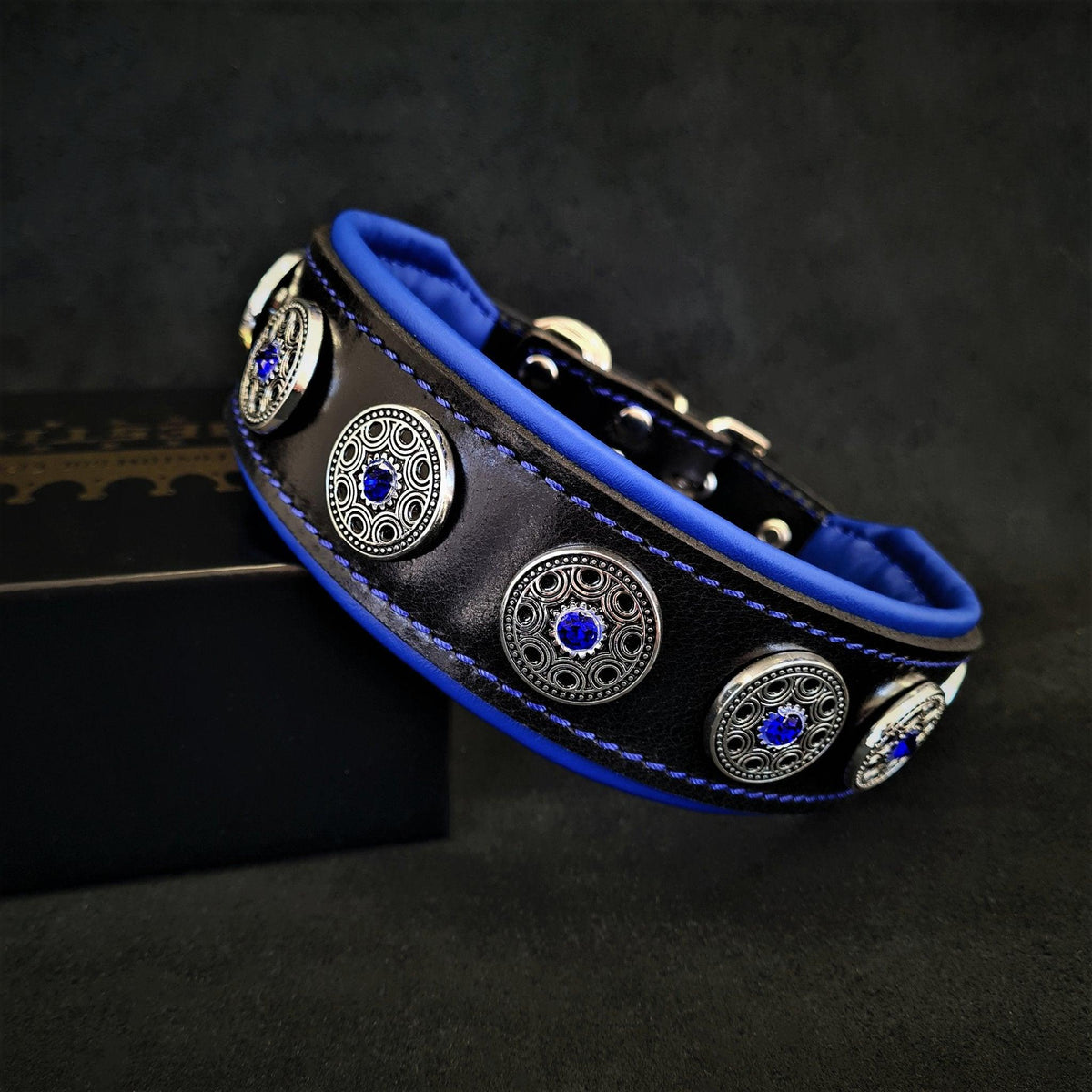 BESTIA Bijou Lederhalsband aus schwarzem Leder mit blauer Polsterung, blauen Nähten und silberfarbenen Ziernieten mit blauen Strasssteinen.
