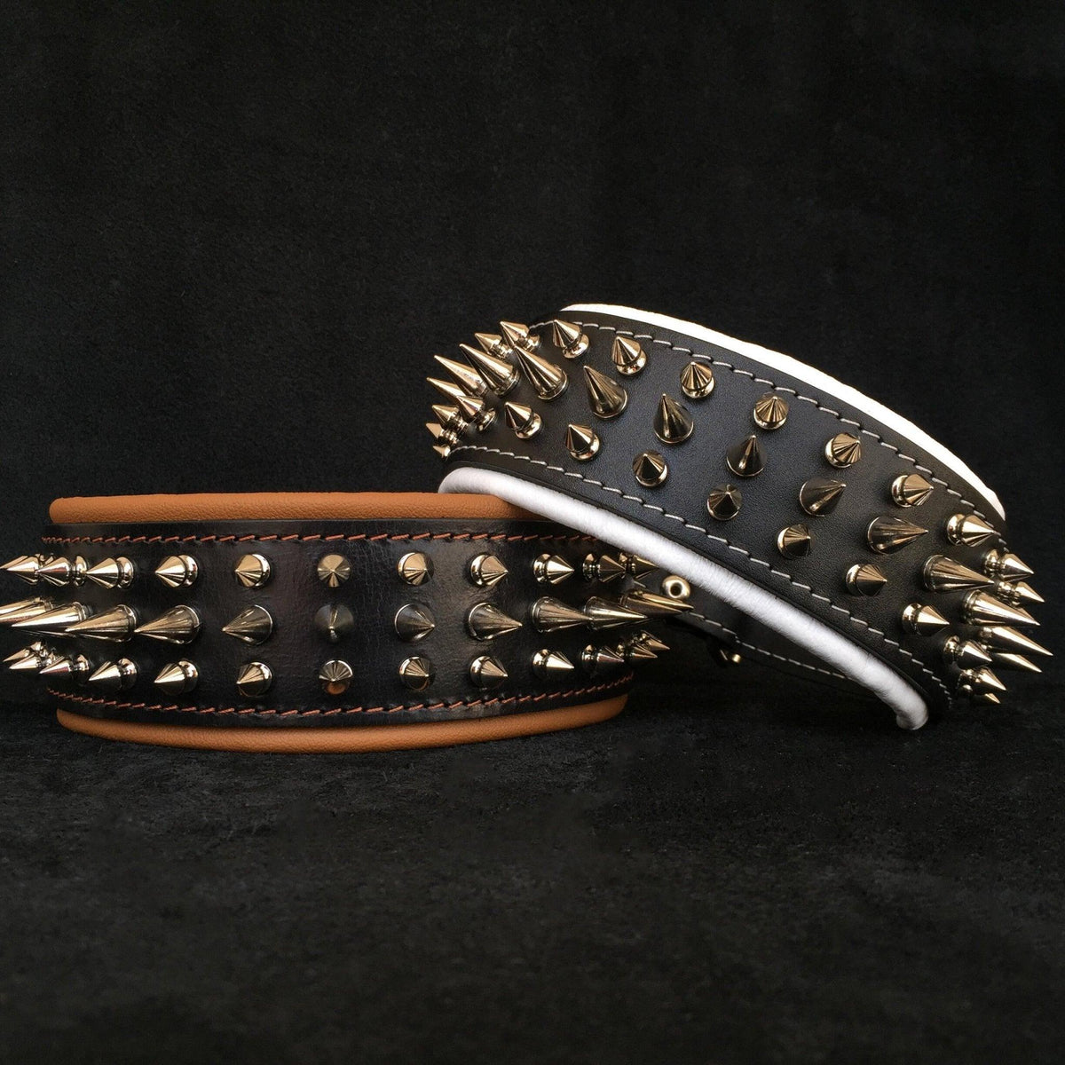 Zwei schwarze Danger-Lederhalsbänder mit metallfarbenen Spikes, eines mit brauner und eines mit weisser Polsterung