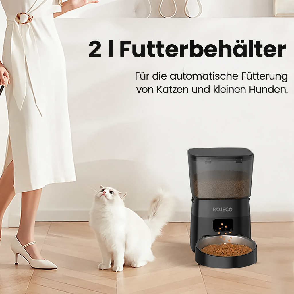 Schwarzer Futterautomat mit 2-Liter-Vorratsbehälter und gefülltem Napf neben einer weissen Katze.
