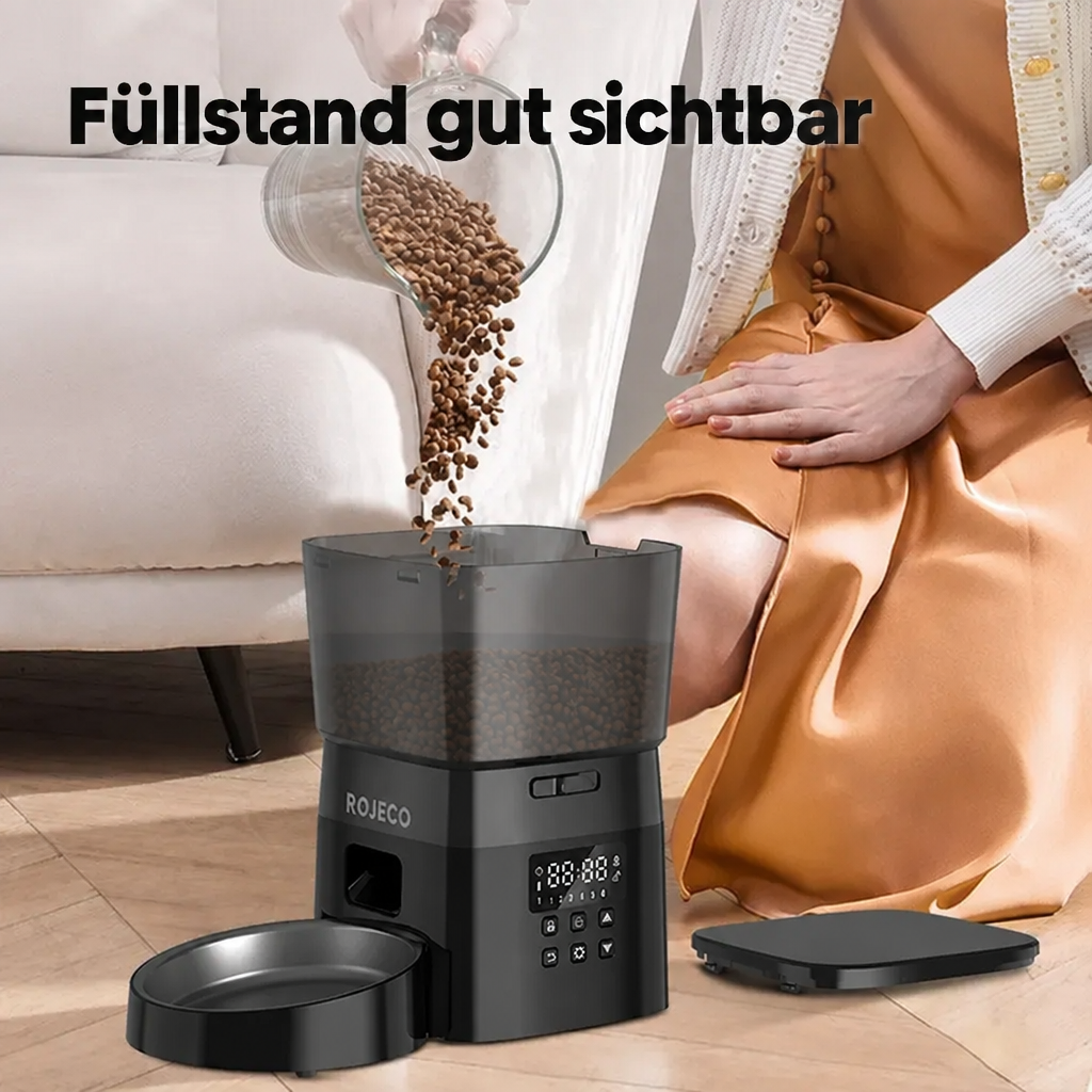 Trockenfutter wird in den geöffneten Futterautomaten gefüllt; der Füllstand ist durch den transparenten Behälter sichtbar.