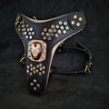 Schwarzes Irondog-Ledergeschirr mit metallfarbenen sechseckigen Zierelementen und rot-goldenem Helm-Motiv auf dunklem Hintergrund
