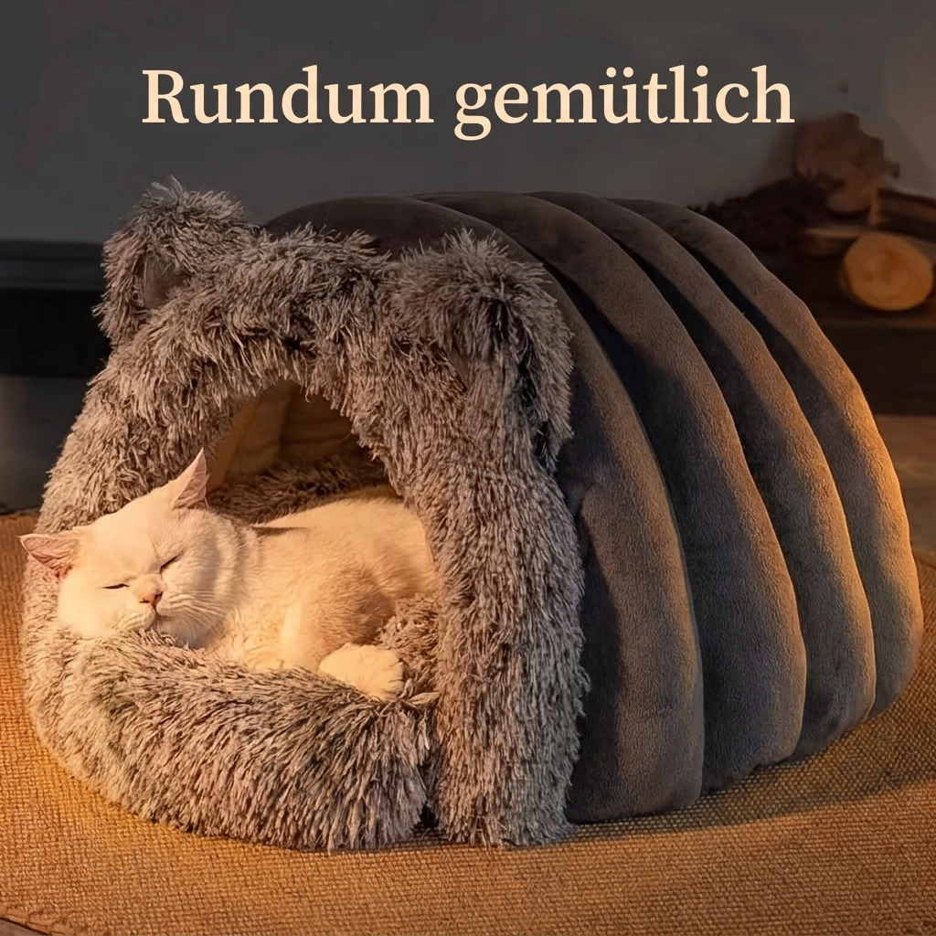Weisse Katze schläft in der grauen Plüsch-Katzenhöhle mit dem Schriftzug «Rundum gemütlich».