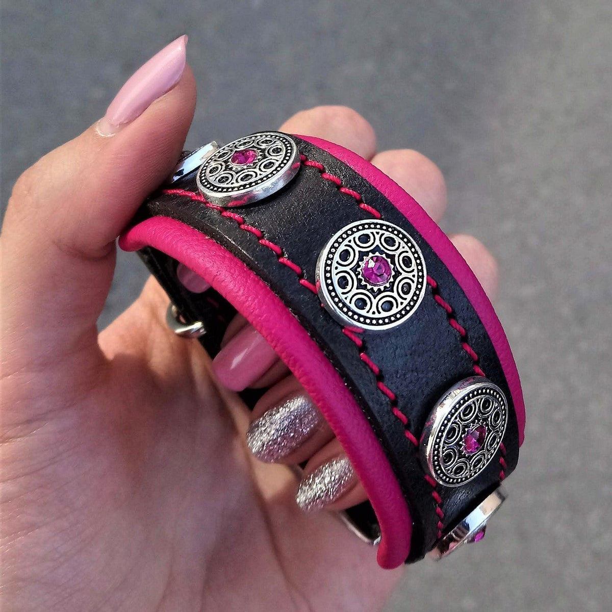 Nahaufnahme des BESTIA Bijou Lederhalsbands mit pinker Polsterung, pinken Nähten und silberfarbenen Zierelementen.