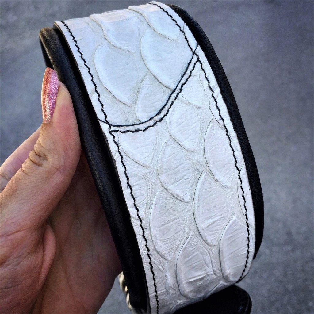 Nahaufnahme des weissen Dragon-Scale-Halsbands mit Schuppenprägung und schwarzen Nähten, in einer Hand gehalten
