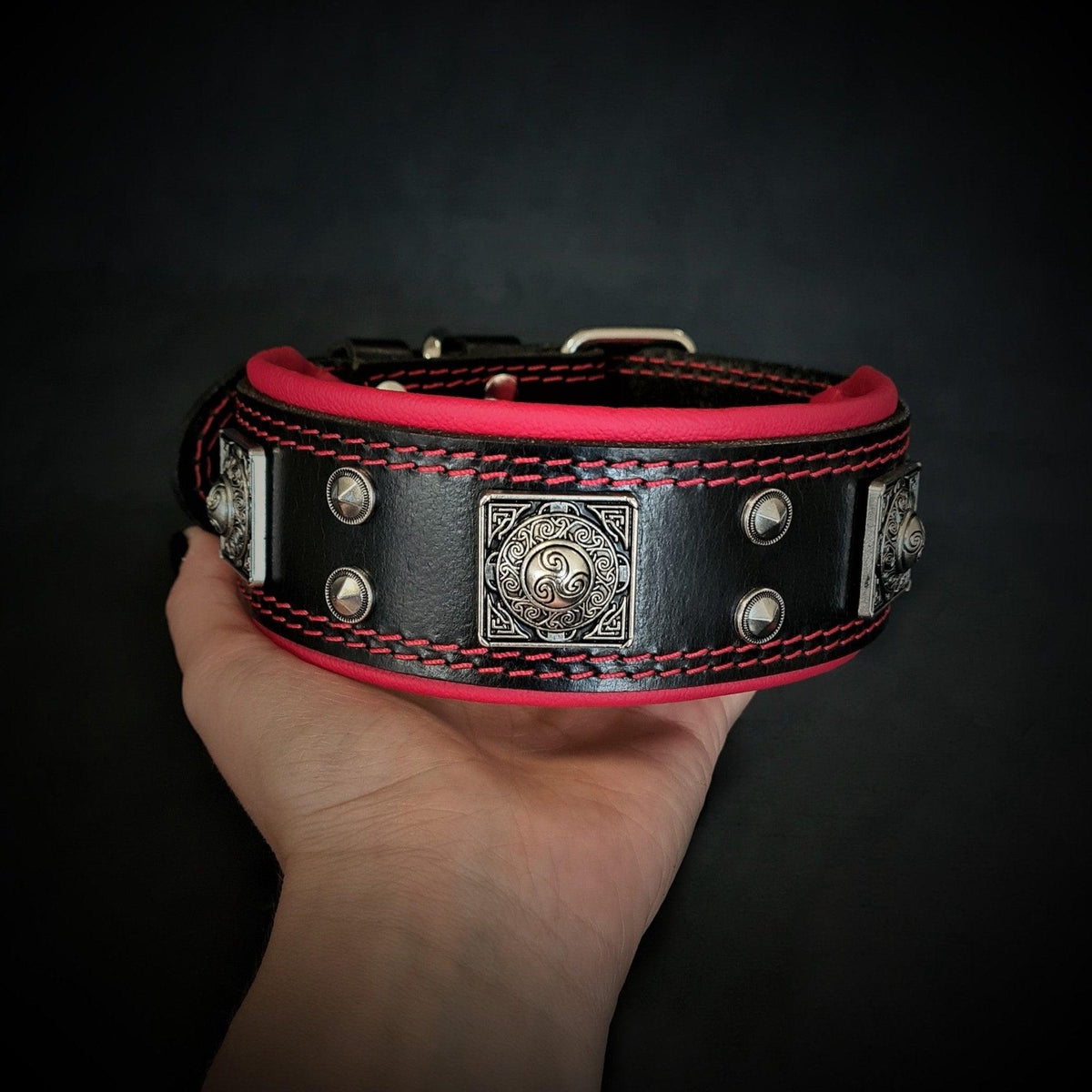 BESTIA Eros Halsband mit roter Polsterung und silberfarbenen Ziernieten, auf einer Hand präsentiert.