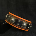 BESTIA Eros Lederhalsband in Schwarz mit orangefarbener Polsterung, orangefarbenen Nähten und silberfarbenen Ziernieten.