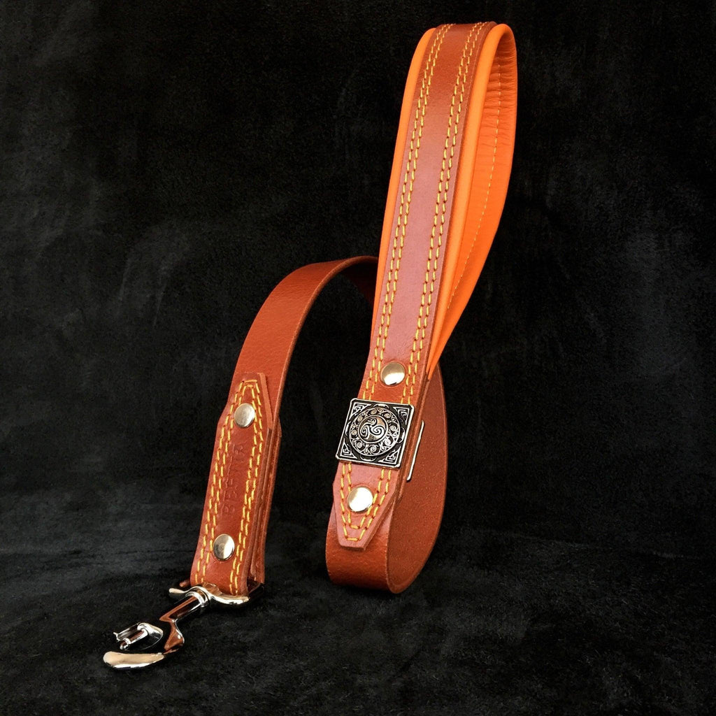 Passende braune BESTIA Eros Lederleine mit orangefarben gepolstertem Griff, quadratischem Zierelement und silberfarbenem Karabiner.
