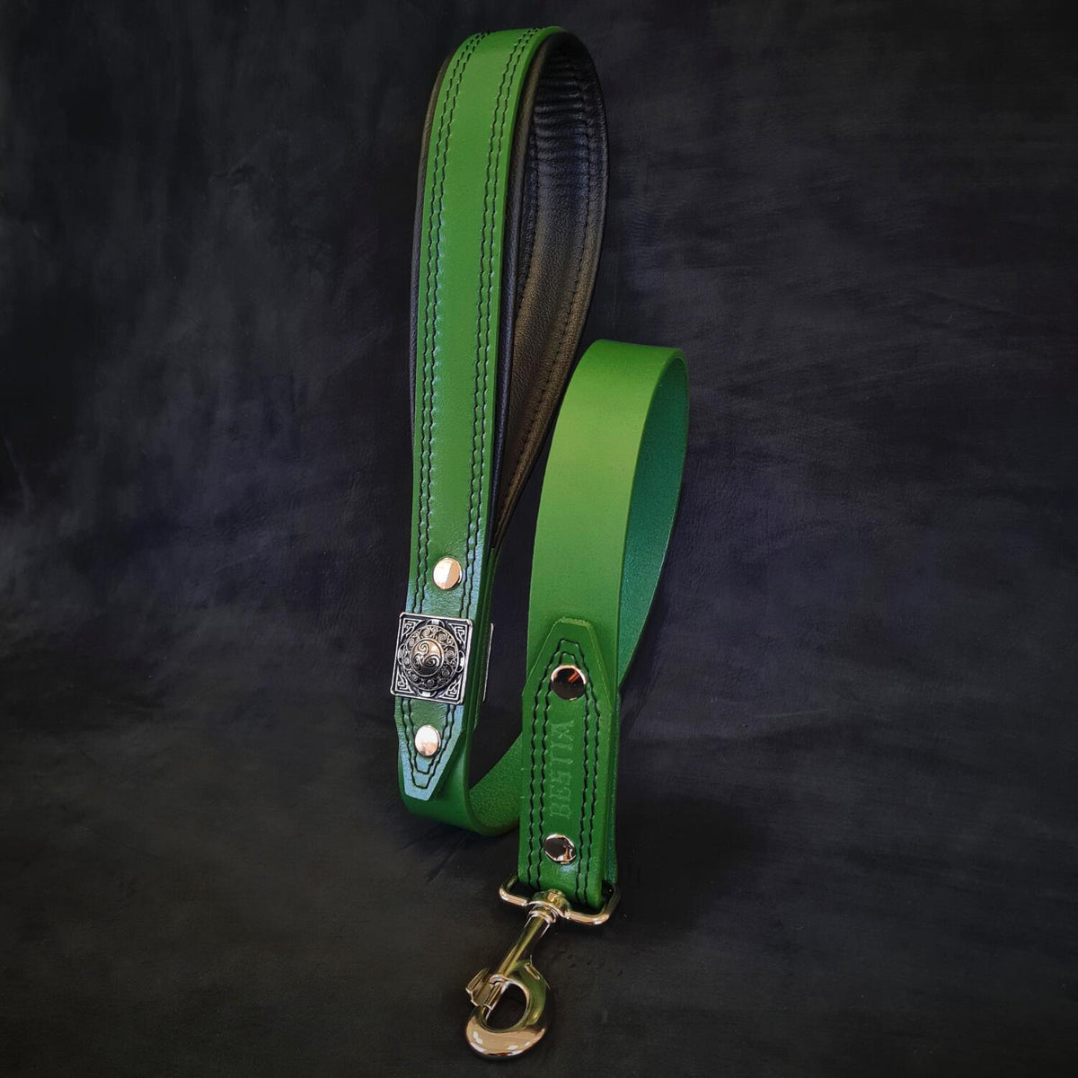 Grüne BESTIA Eros Lederleine mit gepolsterter Handschlaufe, quadratischer Zierniete und Metallkarabiner.