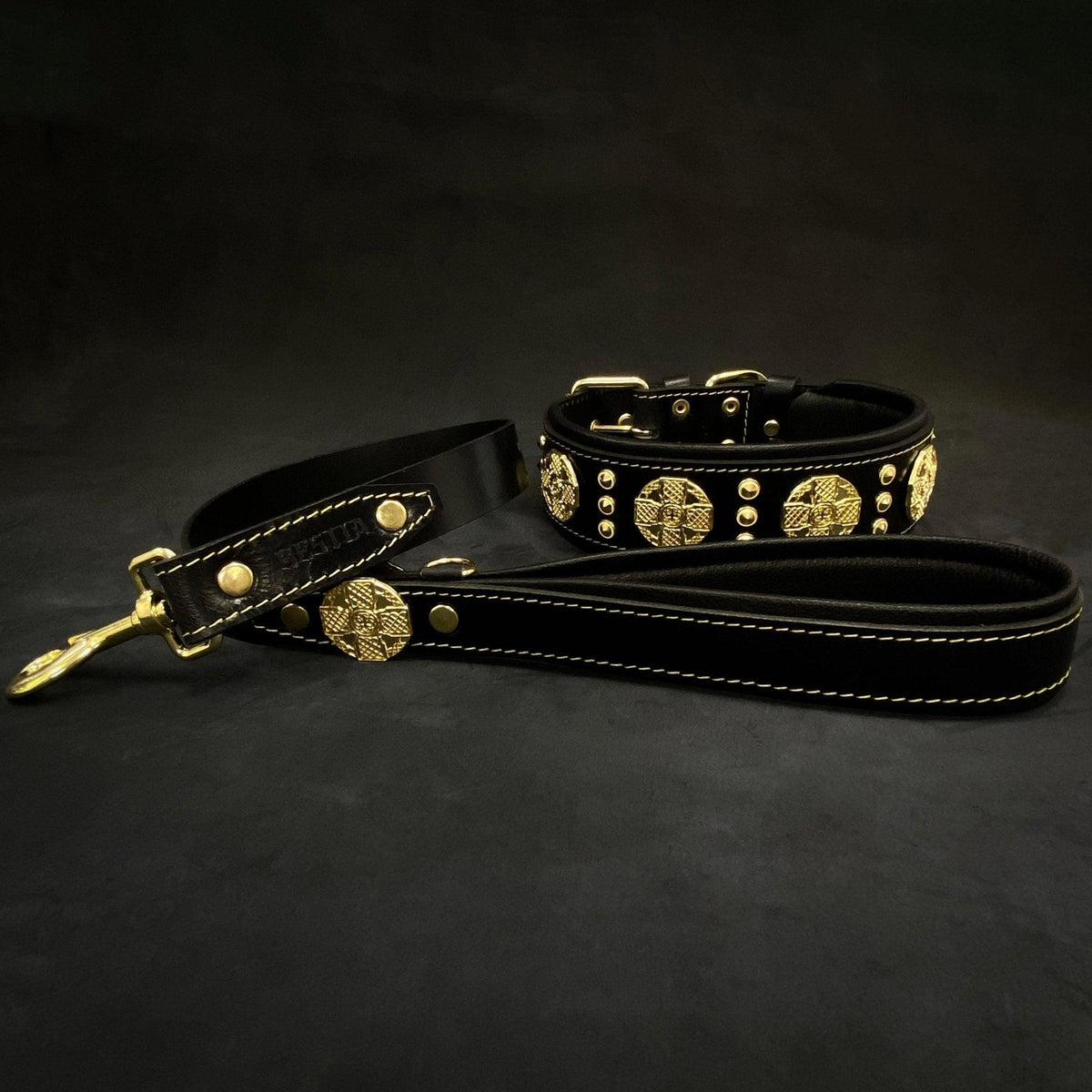 BESTIA Maximus Set aus schwarzem Lederhalsband und passender Leine mit goldfarbenen Ziernieten und Metallbeschlägen.