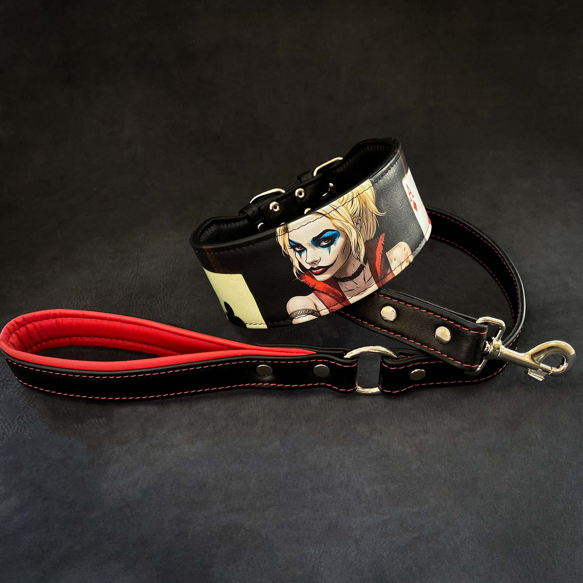 Schwarzes Harley-Halsband mit farbigem Figurenprint neben einer schwarzen Lederleine mit roter Handschlaufenpolsterung und Metallkarabiner